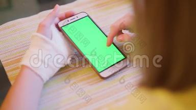 年轻的白种人金发碧眼，左手断了，看着绿色的智能手机屏幕。 近距离观看